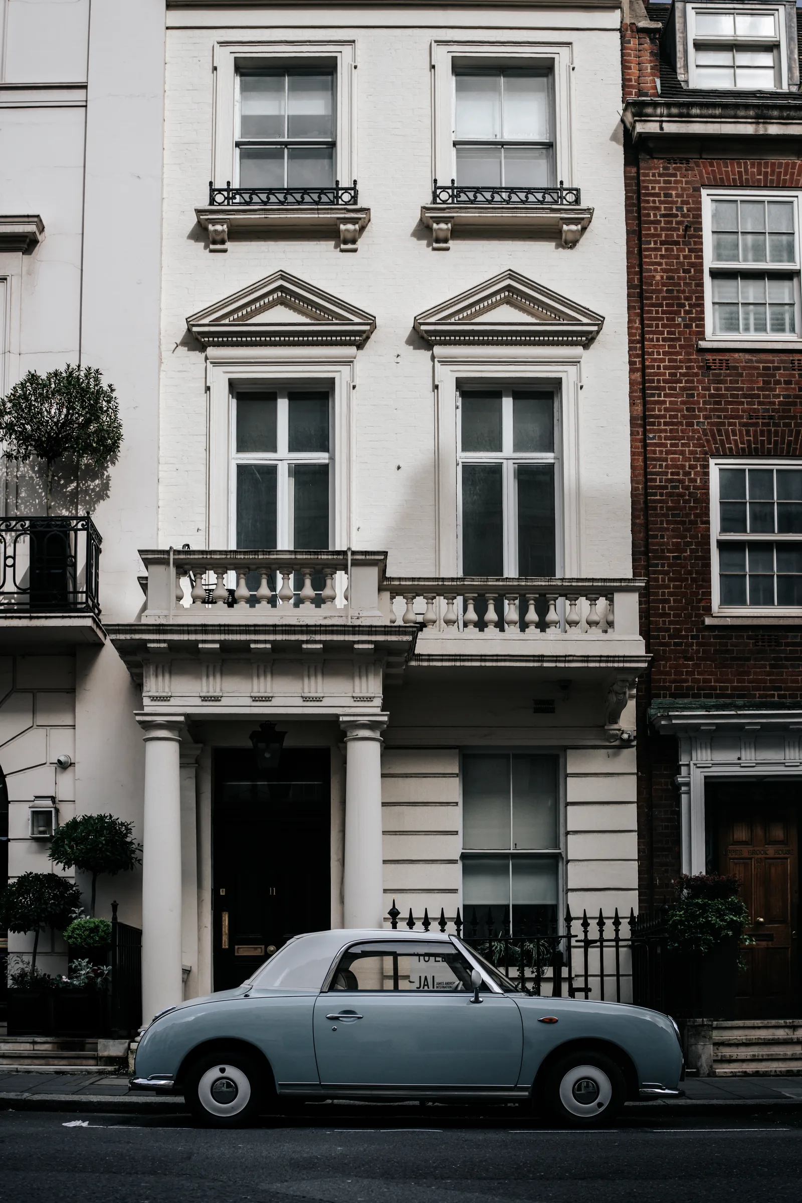 Classic car parked in front of a townhouse.