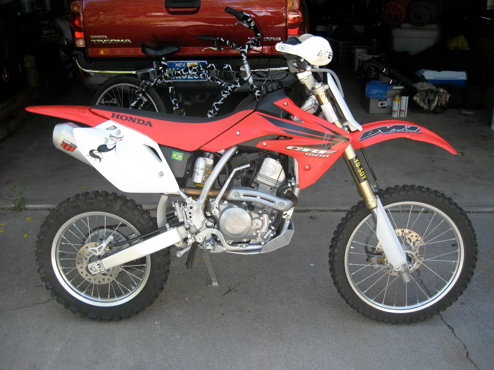Red Honda CRF dirt bike parked in a driveway in front of a garage.