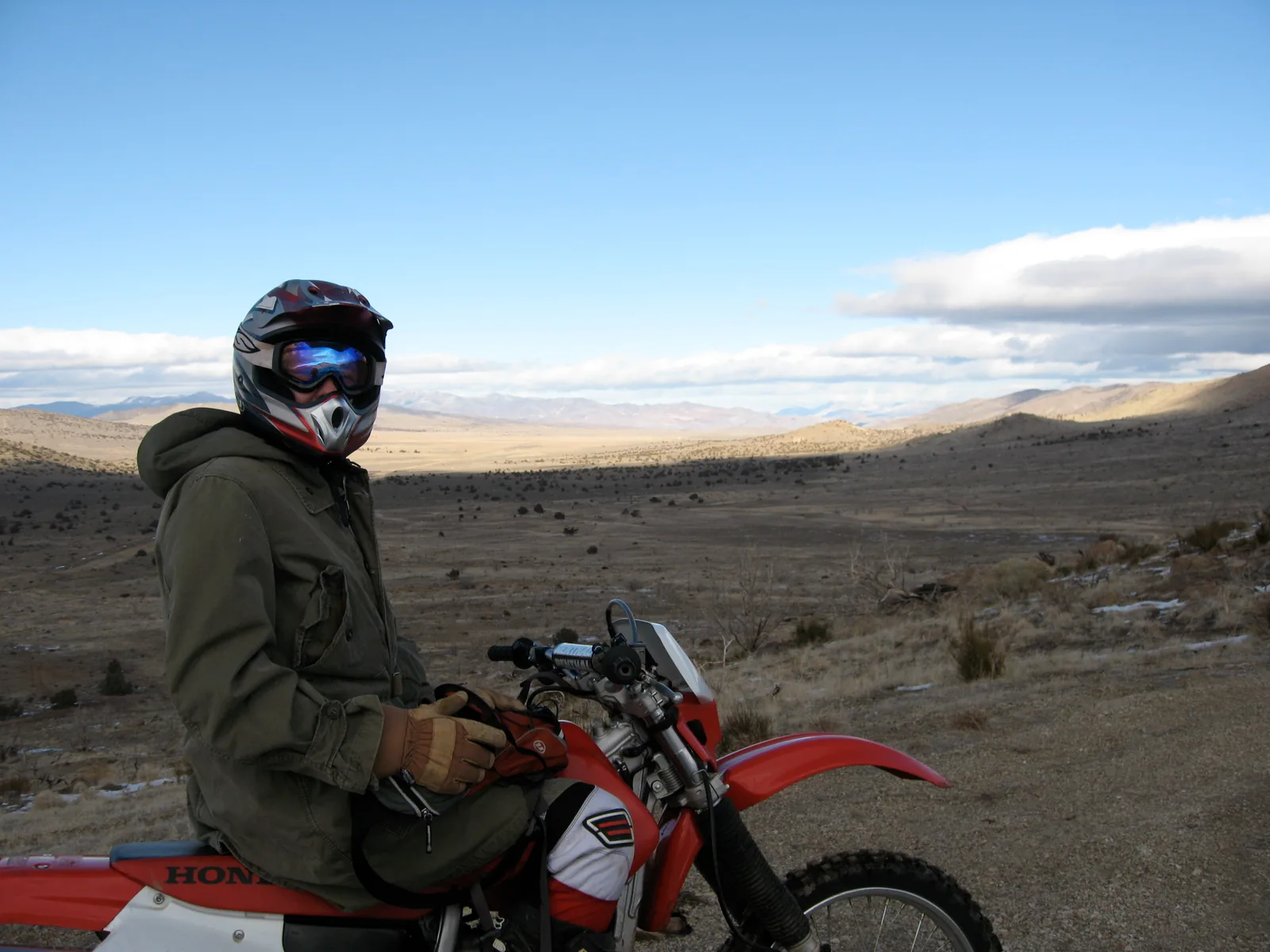 Adventure motorcycle loaded with soft luggage and a top box inside a garage.