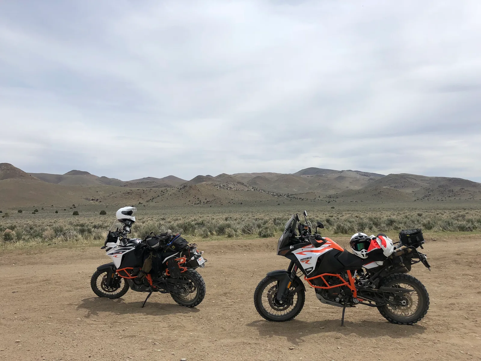 Two loaded KTM adventure motorcycles parked in an open desert landscape.