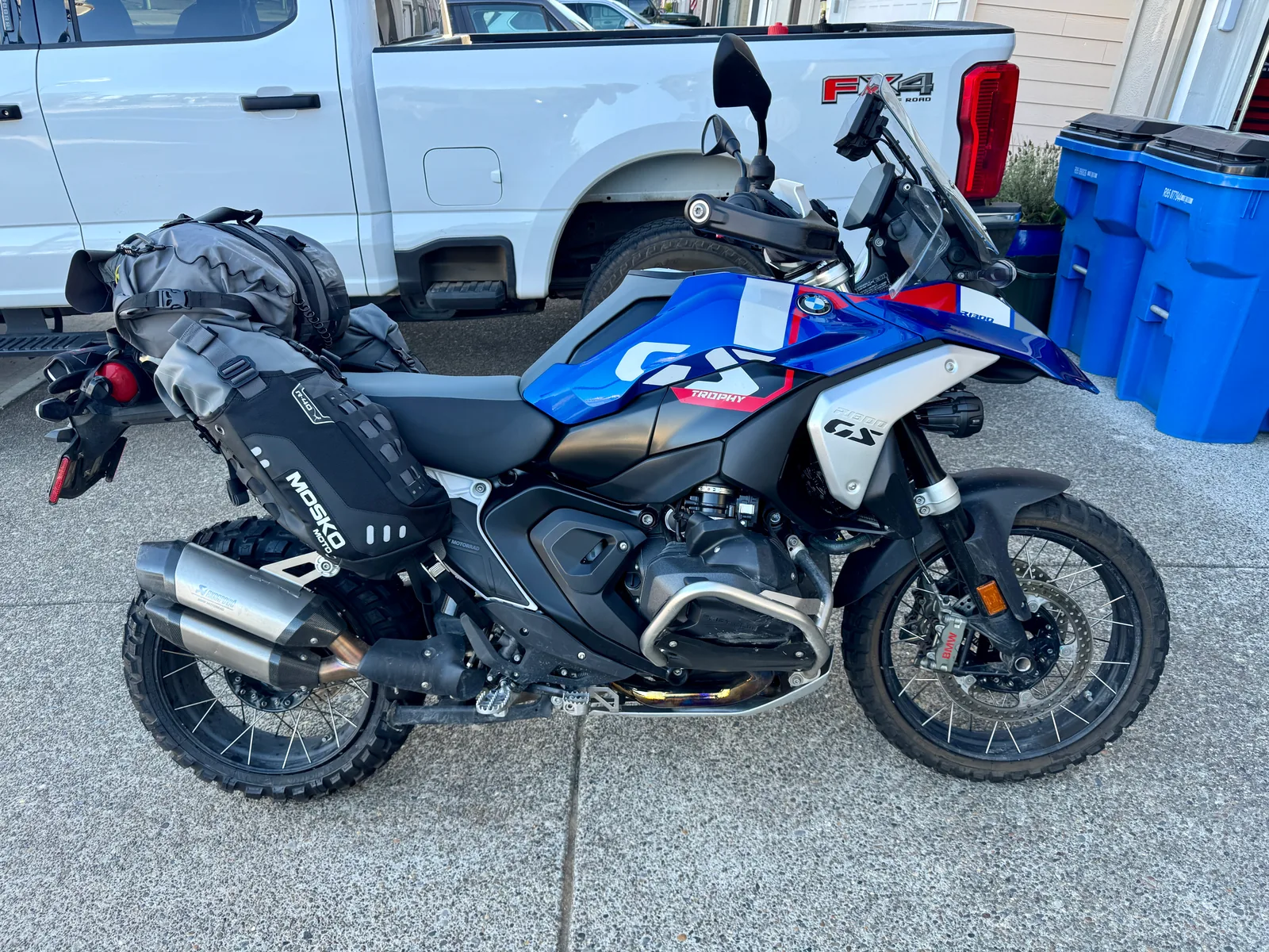 Blue BMW GS motorcycle shown in profile in front of a white pickup truck.